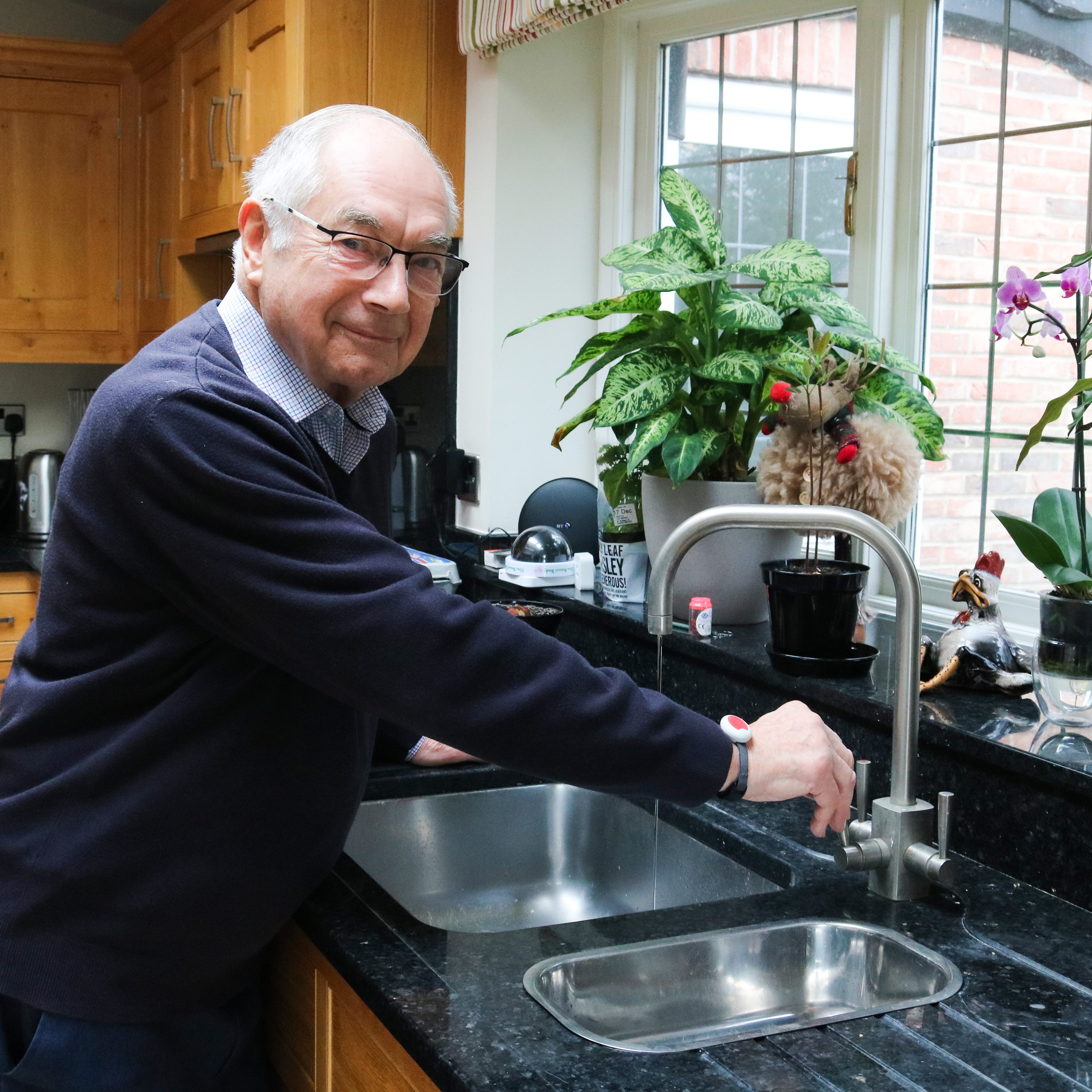 Elderly man wearing his pendant whilst washing up